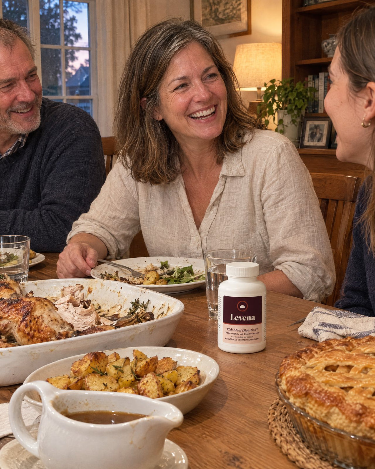 A woman laughing at her dinner table after a home-cooked roast chicken dinner