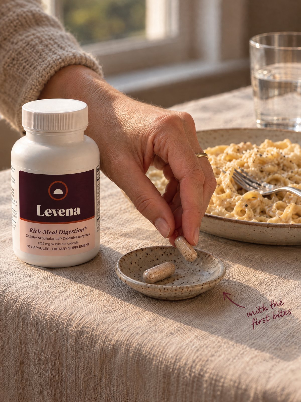 A hand taking one Levena capsule from a small dish at the start of a pasta dinner